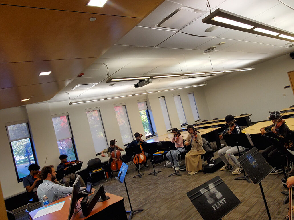 UM-Flint music instructor teaches high school string instrument students in a classroom