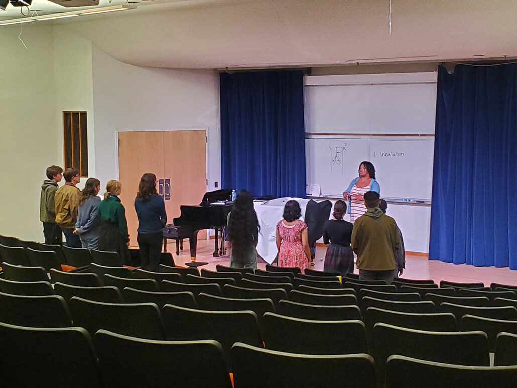 UM-Flint Music instructor teaching a class of high school vocal students in an auditorium-style classroom