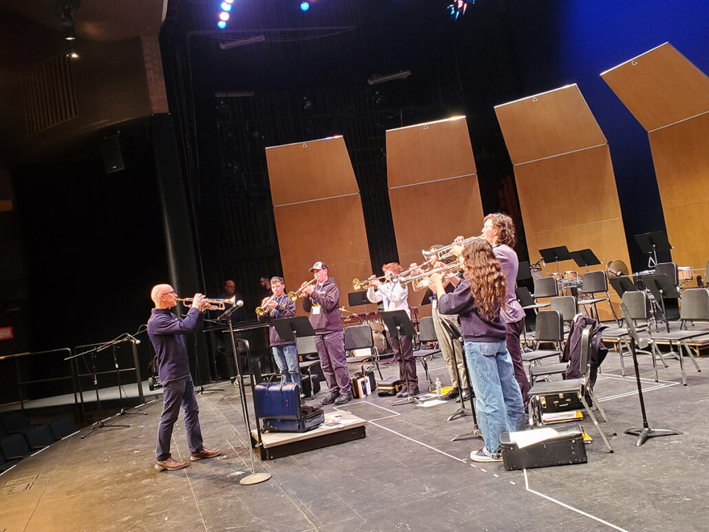 UM-Flint music instructor teaching high school trumpet students on an auditorium's stage