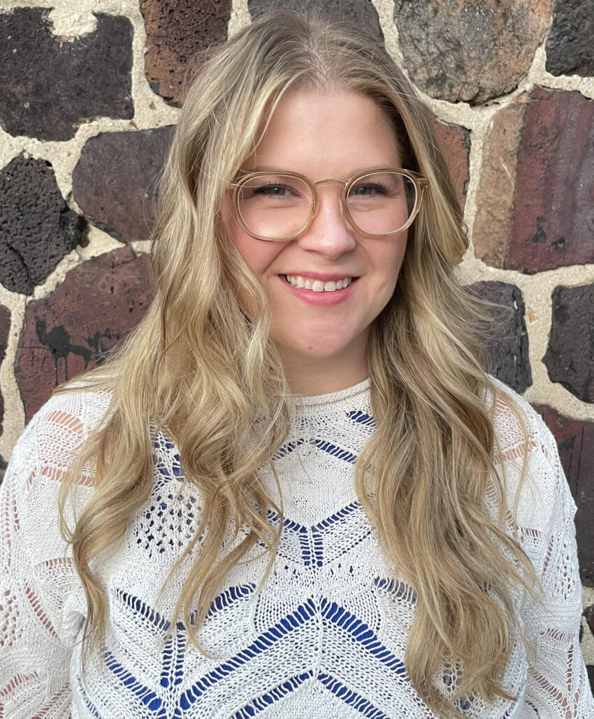 Portrait of a young white woman with long blonde hair smiling at the camera