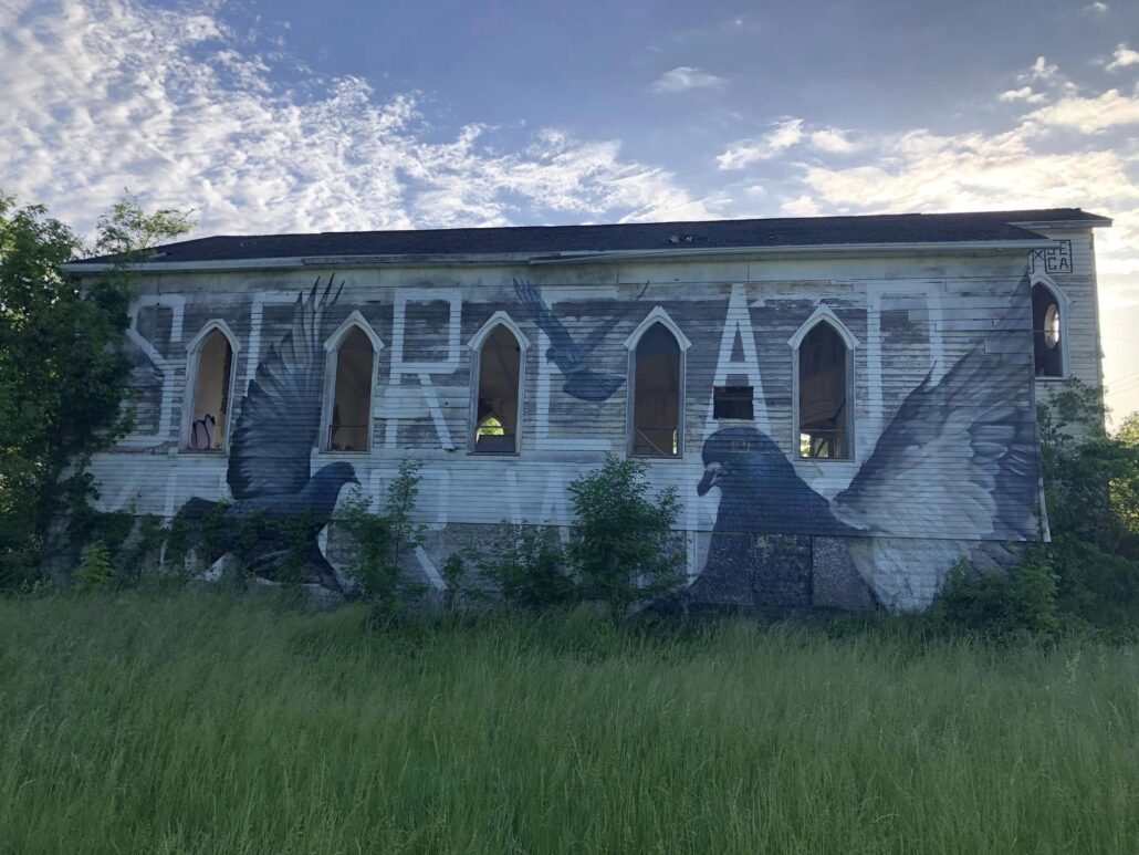 An old church with a mural of pigeons on the outside.