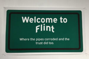 Welcome to Flint sign with the text: "Where the pipes corroded and the trust did too."