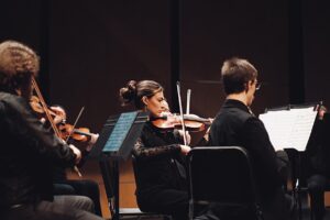 Orchestra musicians playing violins during a performance.