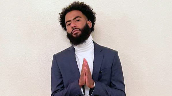 Osman Belal, CHS Alum, in a suit with his hands held in prayer pose.