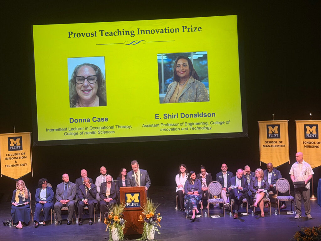 Image of a stage presentation featuring two award recipients, Donna Case and E. Shirl Donaldson, with a group of people seated below.